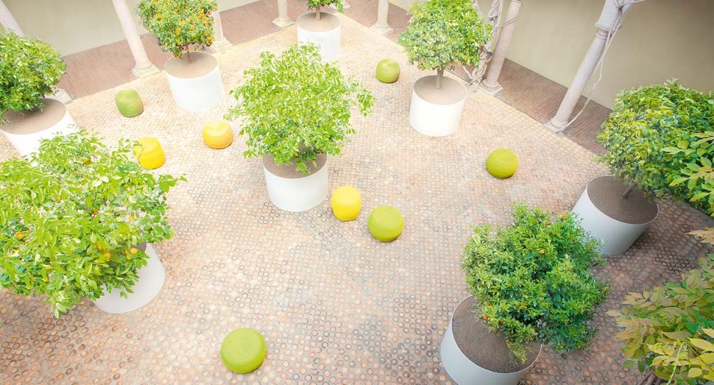 Eight round Otto Pouf, upholstery in rope cord , four in green and three in yellow in an indoor garden.
