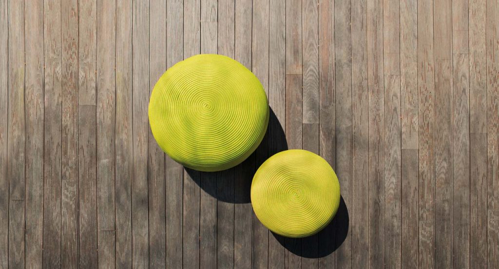 Two round Otto Poufs, upholstery in rope cord , one in green and one in yellow on a brown floor.