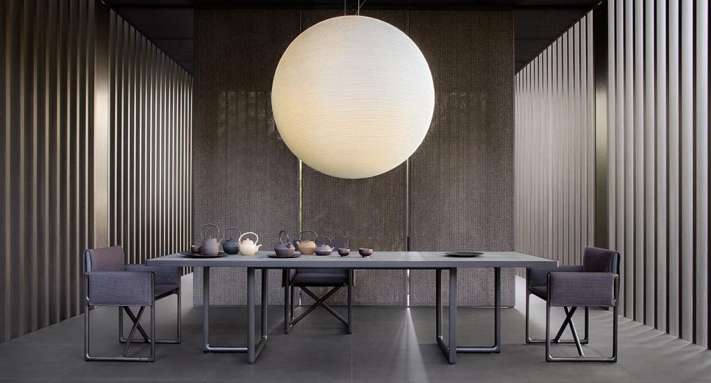 Large Portofino Outdoor Dining Table, two legs in dark heartwood, top in natural lava stone in a dining room.