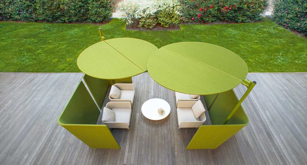 Four beige Sabi Armchairs, base and two legs made of natural wood, backrest in woven rope cord and cushion in fabric in a terrace.
