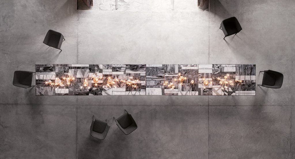 Grey, white and brown Sciara Dining Table, structure and two legs in black steel, top in lava stone in a dining room.