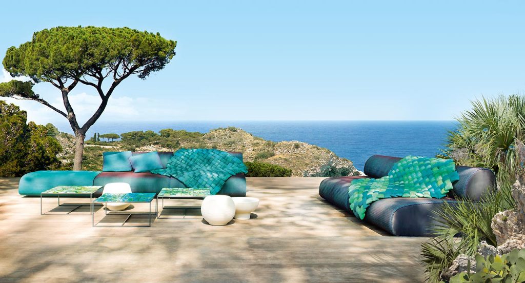 Three Sciara Side Tables, structure in black steel, top in lava stone, two in green and one in blue in a terrace.