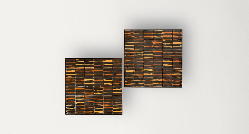 Two square Segni side tables, structure and two legs in black steel, top in brown, orange, yellow ceramic lines on a white background.