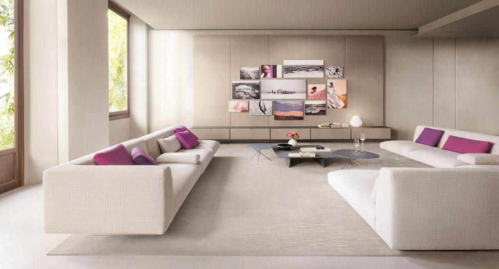 Two Move Sofas, upholstered in white fabric, two legs in steel in a living room.