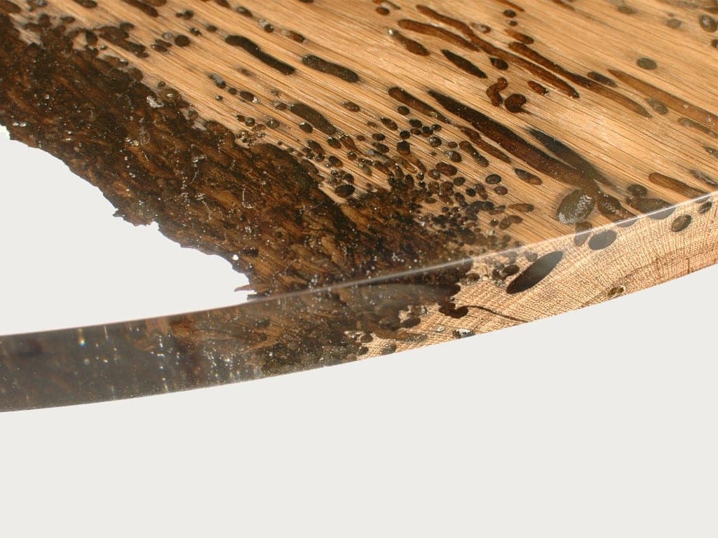 Closeup of Chimenti Round Table with a circular shape, made of solid wood with a natural finish and featuring a transparent resin inlay, set against a white background.