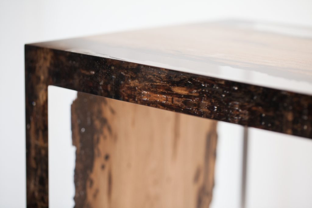 Closeup of Bent River Console with an elongated shape, made of solid wood with a natural finish and featuring a transparent resin inlay, on a white background.