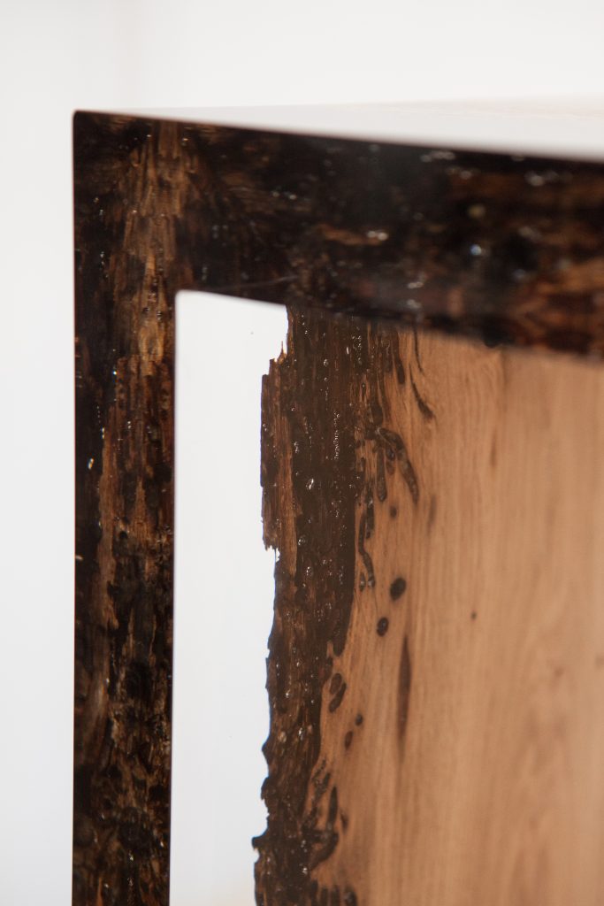 Closeup of Bent River Console with an elongated shape, made of solid wood with a natural finish and featuring a transparent resin inlay, on a white background.
