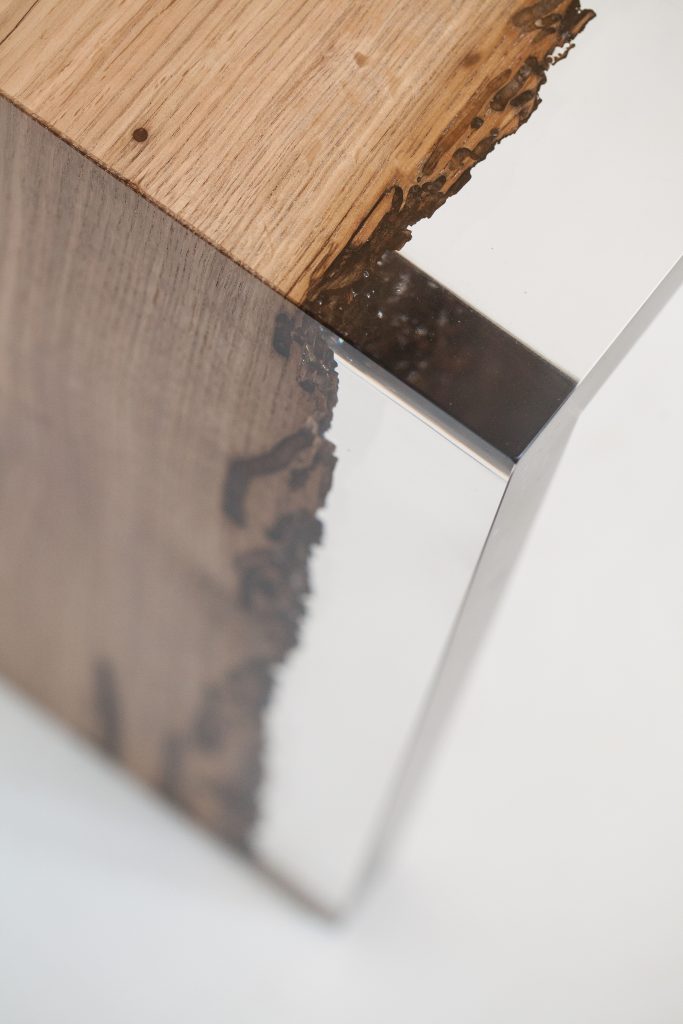 Closeup of Bent River Console with an elongated shape, made of solid wood with a natural finish and featuring a transparent resin inlay, on a white background.