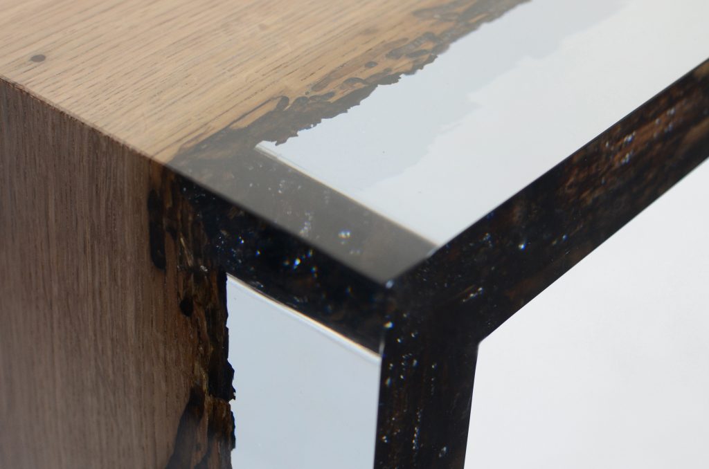 Closeup of Bent River Console with an elongated shape, made of solid wood with a natural finish and featuring a transparent resin inlay, on a white background.