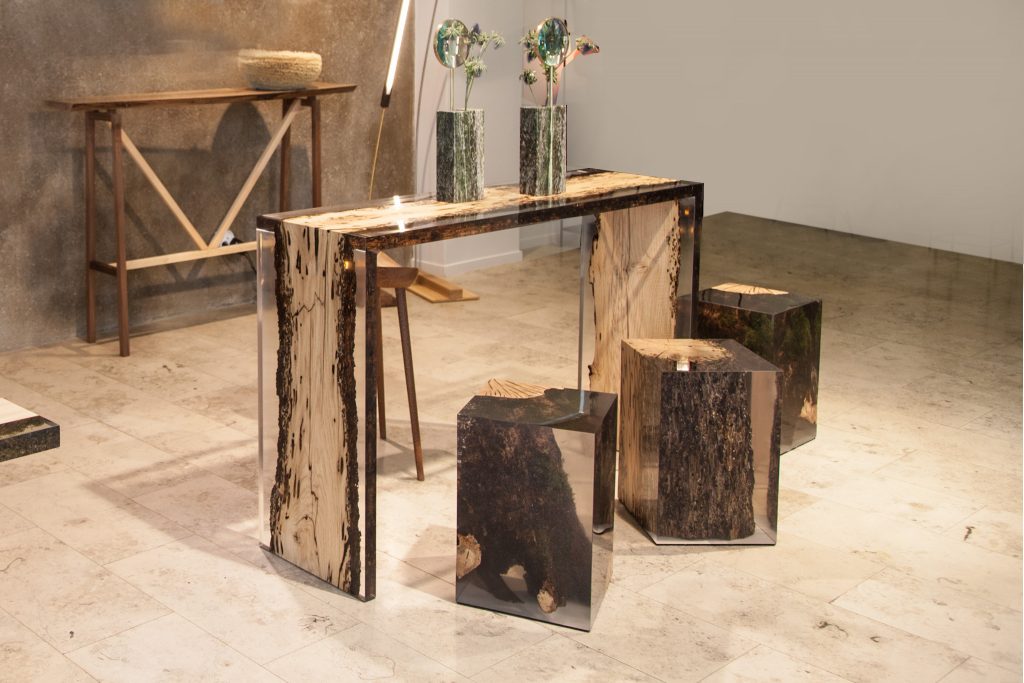 Three Anchor Stool/Side Tables with a cubic shape, made of solid wood and transparent resin inlays, in a showroom.