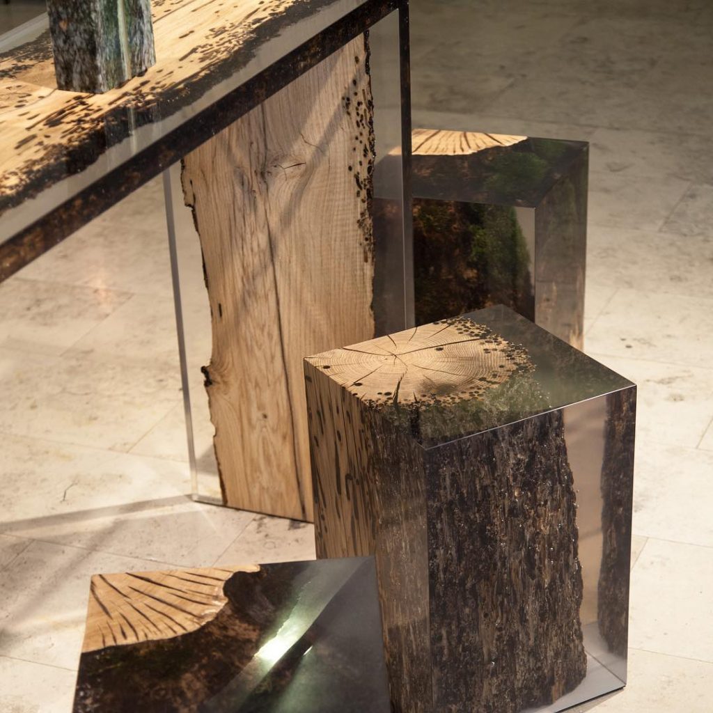 Three Anchor Stool/Side Tables with a cubic shape, made of solid wood and transparent resin inlays, in a showroom.