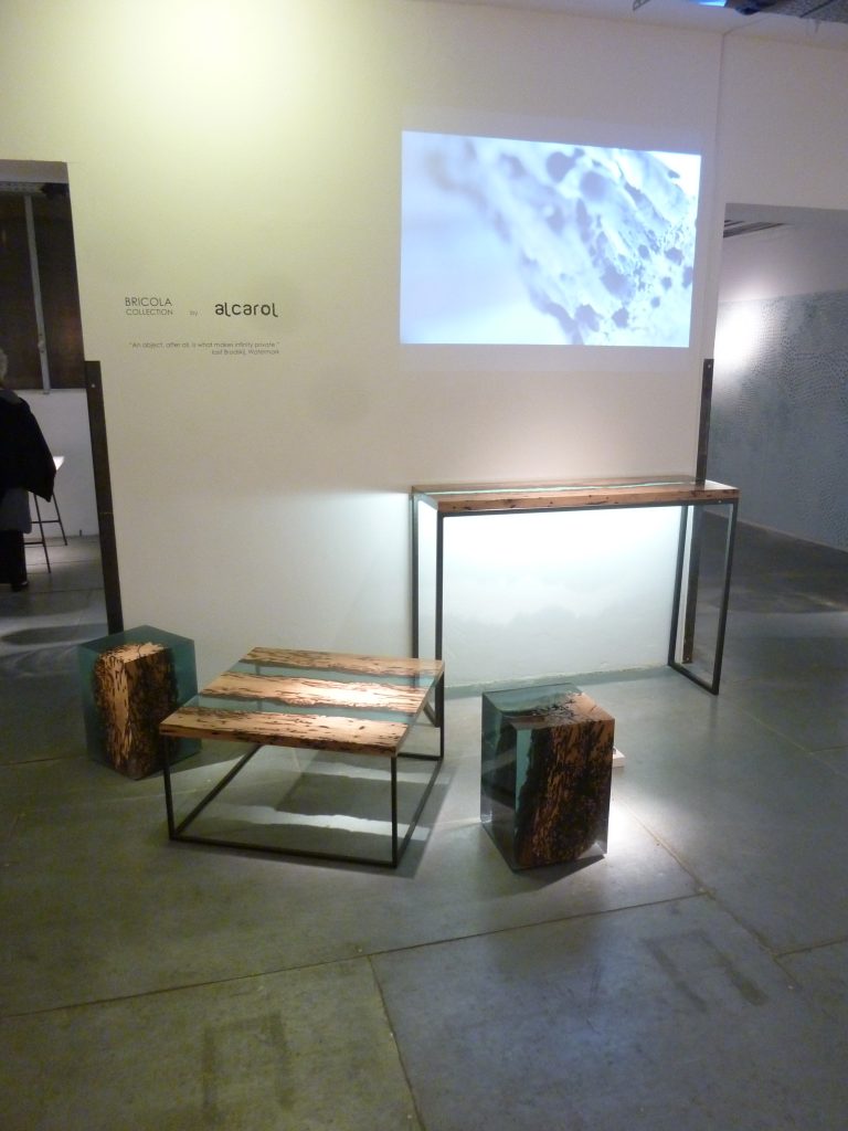 Two Anchor Stool/Side Tables with a cubic shape, made of solid wood and transparent resin inlays, in a showroom.