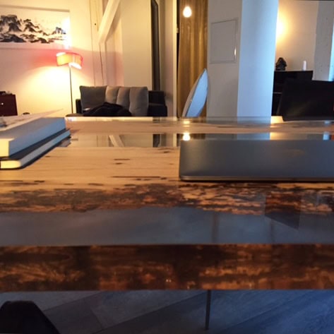 Closeup of Bent Desk with a rectangular shape, made of solid wood with a natural finish and featuring a transparent resin inlay, in an office.