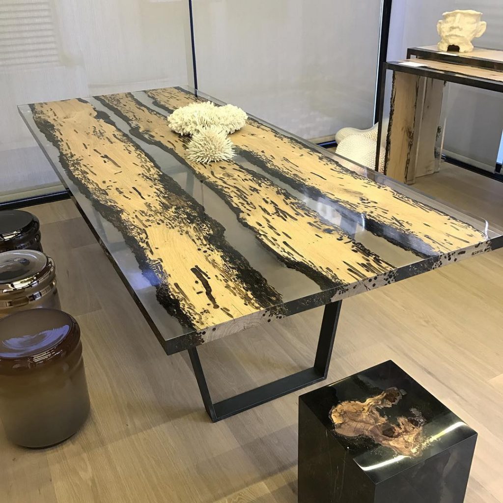 Chimenti Table with an elongated, organic shape, made of solid wood with a natural finish and featuring a transparent resin inlay, in a living room.