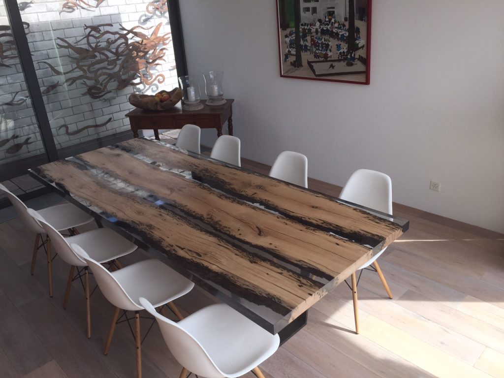 Chimenti Table with an elongated, organic shape, made of solid wood with a natural finish and featuring a transparent resin inlay, in a living room.