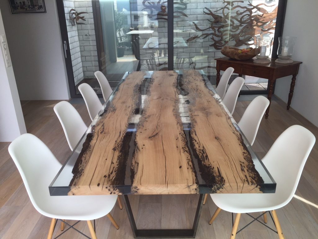 Chimenti Table with an elongated, organic shape, made of solid wood with a natural finish and featuring a transparent resin inlay, in a living room.