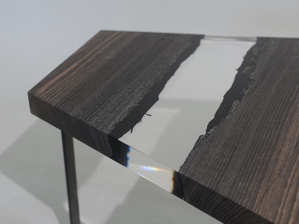 Closeup of Crystal Peatwood Low Table with an polygonal shape, made of solid peatwood with a natural finish and featuring a transparent resin inlay, set against a white background.