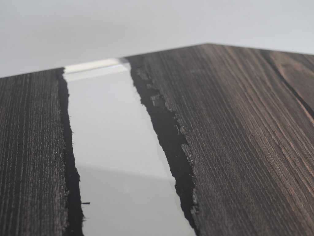 Closeup of Crystal Peatwood Low Table with an polygonal shape, made of solid peatwood with a natural finish and featuring a transparent resin inlay, set against a white background.