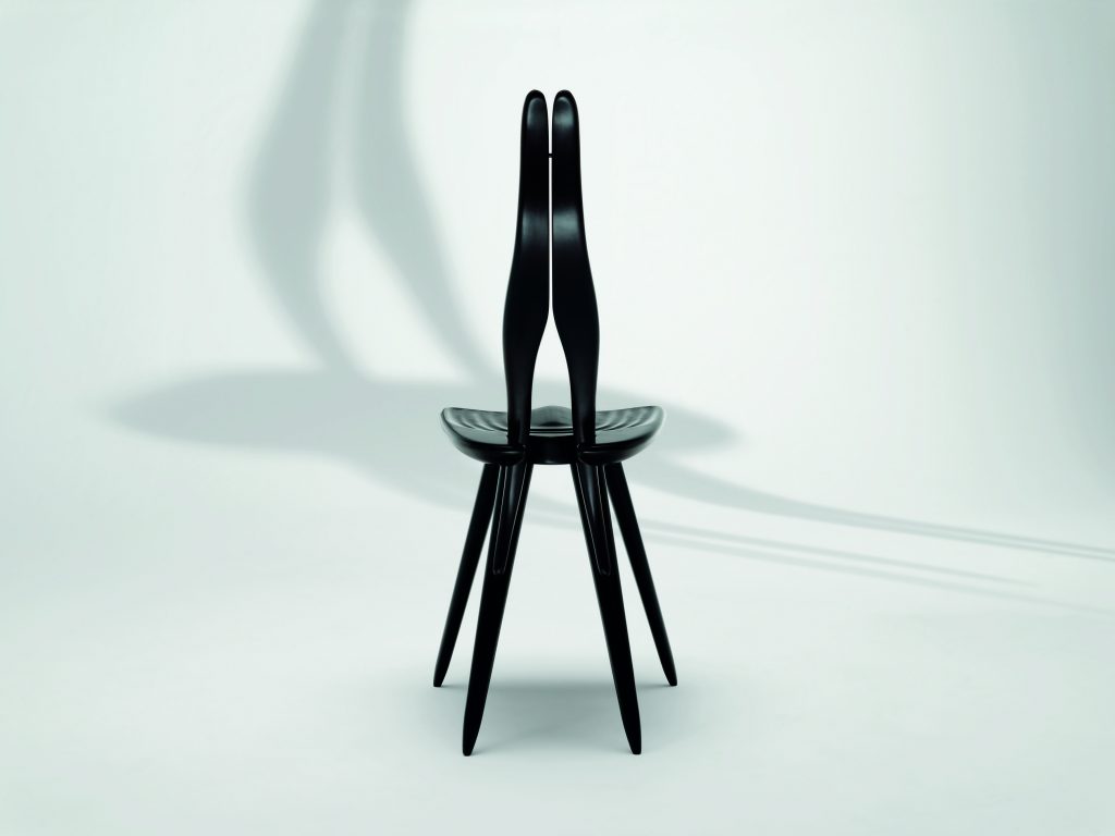 Fenis chair with a black frame, rabbit ears like shape back on a white background.