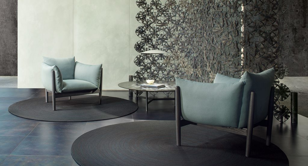 Tapio Armchair, upholstery in blue fabrics, structure and four chairs in black wooden in a living room.