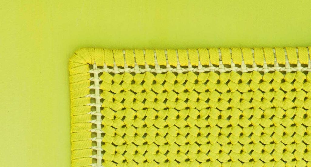 Siepe rug, embroidery made of flat braid in kimia yellow and brown fabric on a yellow background.