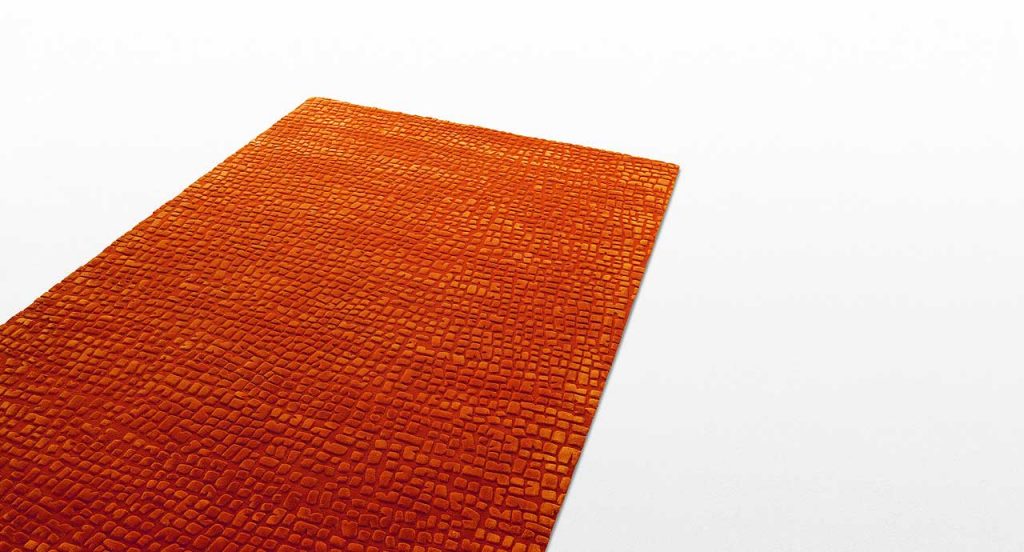 Red Signs rug, irregular geometric shapes in relief made of silk and wool on a white background.
