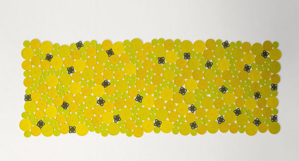 Spin off rug, made of yellow, green and brown sewn spirals on a white background.