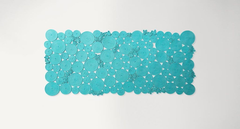 Spin off rug, made of blue sewn spirals on a white background.