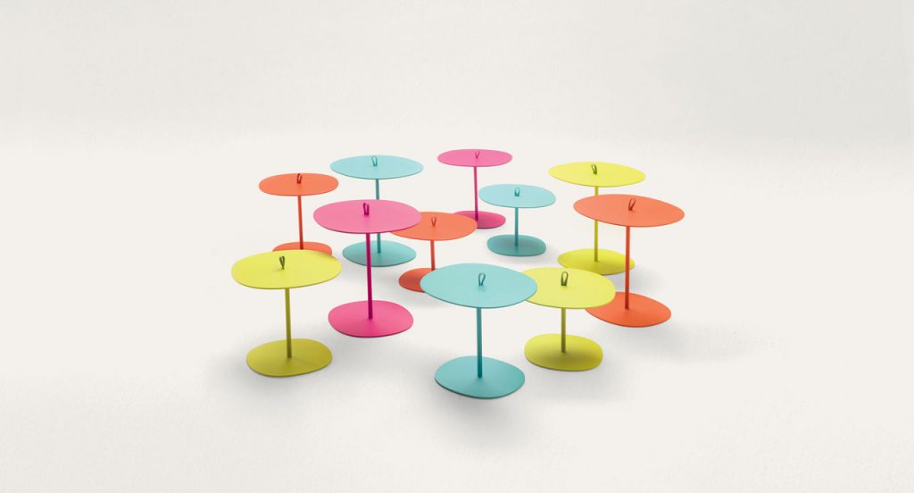 Eleven round Strap sides tables, three in green, three in orange, three in blue and two in pink. Aluminium structure on a white background.