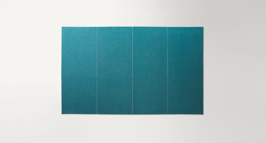 Green Unito rug made of two layers of felt with punyo cavallo border stitching on a white background.