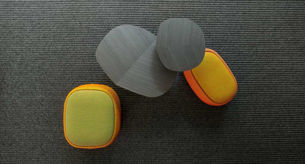 Two Smile Indoor Pouf, upholstered in blend y dots fabric , one in green and yellow, one in orange and yellow in a living room.