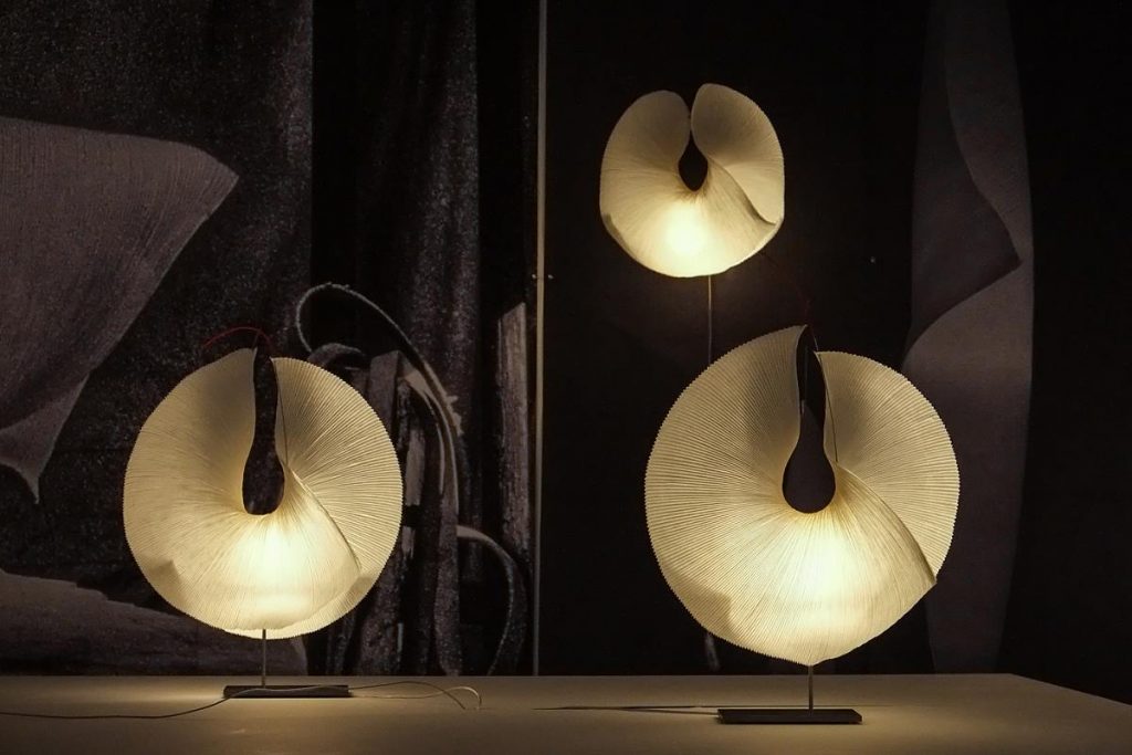A table with three Yoruba Rose lamps on top of it in a dark setting