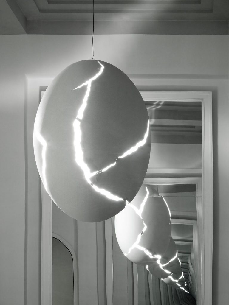A Broken Egg light hanging in front of a mirror in a white room