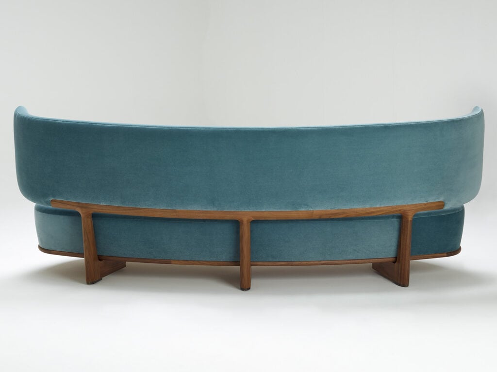 large cushion made of blue-colored fabric and resting on brown-colored wood on a white backgrond