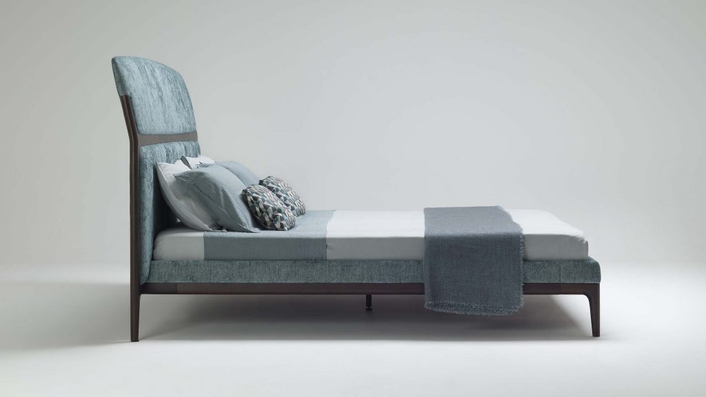 bed made of a wooden base upholstered in velvet fabric in a tone of blue with white on a white background