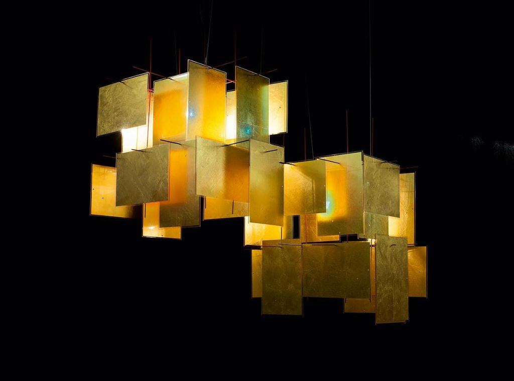A 1000 Karat chandelier hanging from a ceiling in front of a black background