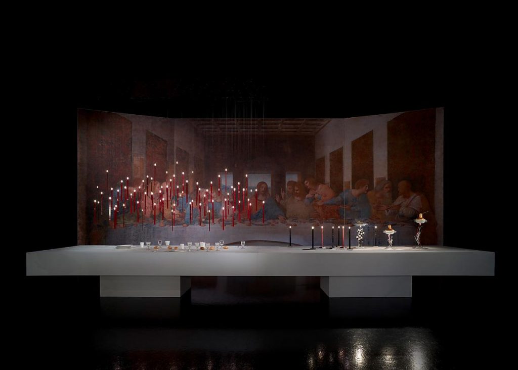 A background of a group of people standing behind a table with Flying Flames hanging from the ceiling over the table