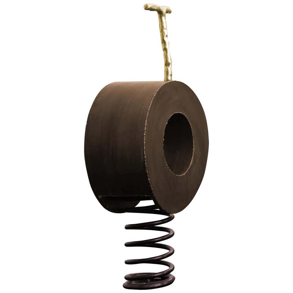 sculpture made of a wooden base and a large spring in a brown tone with gold with a circle design on a white background