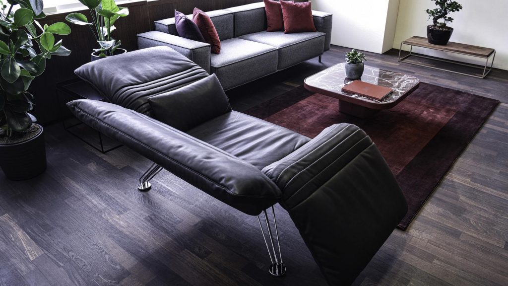 Multifunctional chaise made of aluminum base and upholstered in black leather in a living room