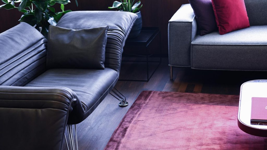 Multifunctional chaise made of aluminum base and upholstered in black leather in a living room