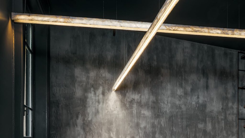 two long lamps made of white glass stone and steel in a gold tone with black