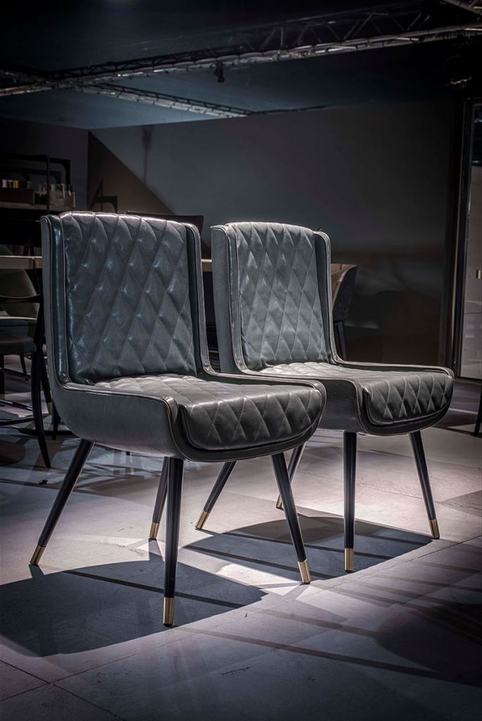 two chairs made of a wooden base with brass tops upholstered in dark blue leather