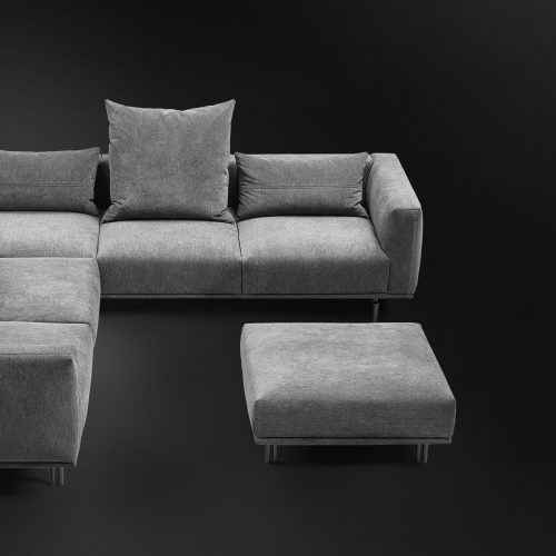 L-shaped sofa made on the basis of wooden legs and upholstered in gray fabric and cushions filled with feathers on a black background