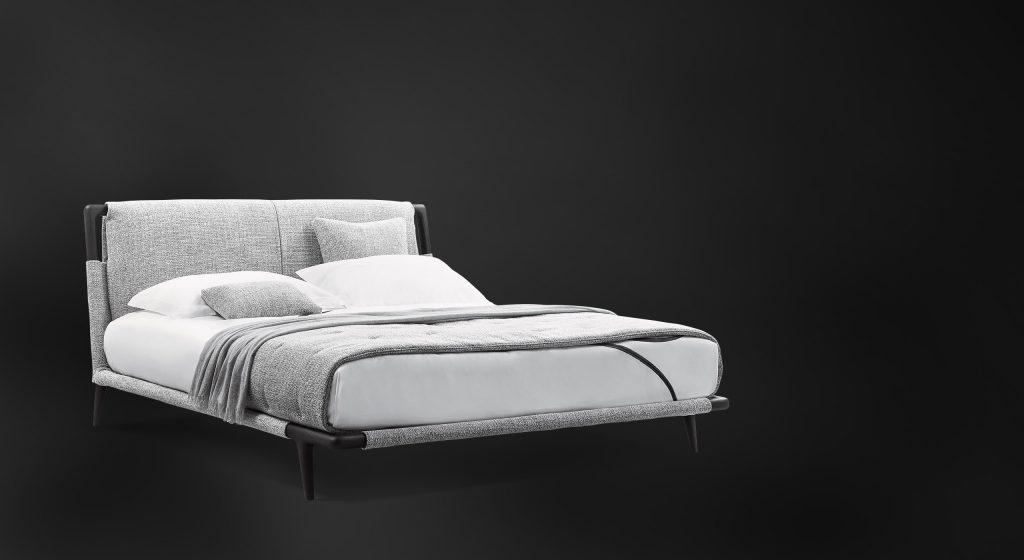 headboard and footboard made of wood and upholstered in light gray fabric on a black background
