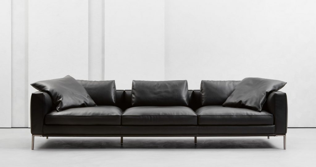 metal base and aluminum feet upholstered in black leather filled with goose down on a white background