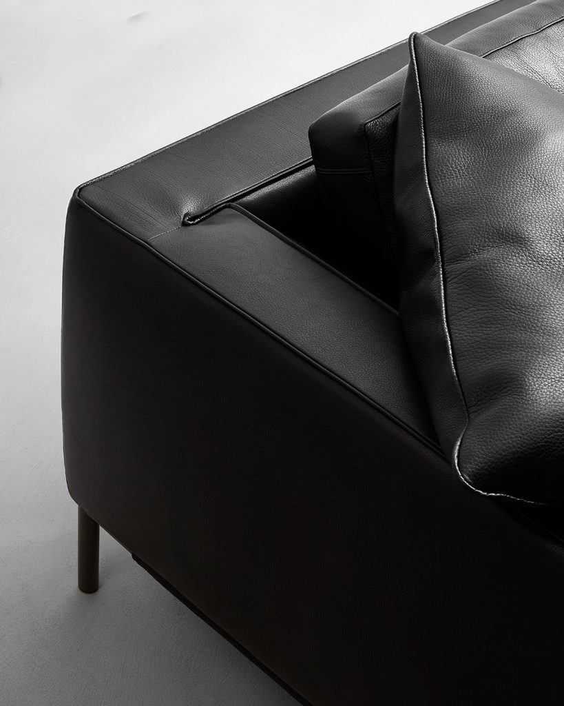 sofa made of wood upholstered in shiny black leather on a white background