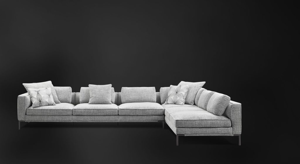 large L-shaped sofa made with aluminum legs and upholstered in white fabric on a black background