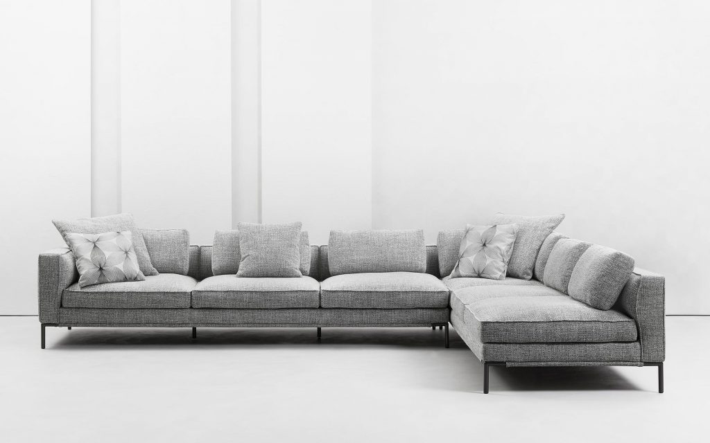 large L-shaped sofa made with aluminum legs and upholstered in white fabric on a white background