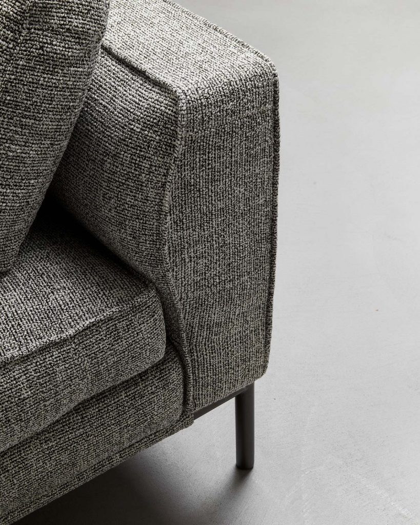 upholstered in textile fabric in a gray tone with white resting on black lacquered aluminum legs