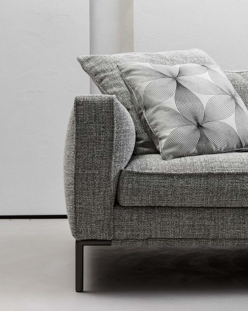 upholstered in textile fabric in a gray tone with white resting on black lacquered aluminum legs on a white background